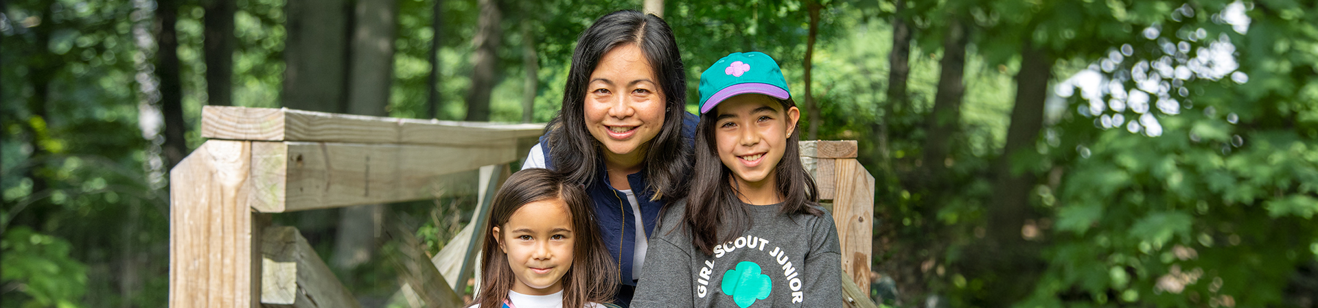  Troop leader with two Girl Scouts smiling outdoors 